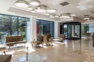 een lobby met stoelen en tafels en grote ramen bij Ramada by Wyndham Slatina Parc in Slatina