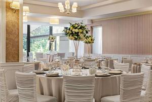 um salão de banquetes com mesas brancas, cadeiras e flores em Ramada by Wyndham Slatina Parc em Slatina