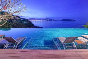 una piscina con sillas y vistas al agua en Zenmaya Oceanfront Phuket, Trademark Collection by Wyndham, en Patong Beach