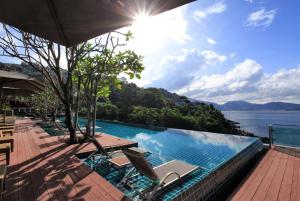 a pool with chairs and a view of the water at Zenmaya Oceanfront Phuket, Trademark Collection by Wyndham in Patong Beach