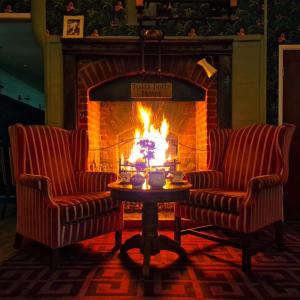 2 sillas y una mesa frente a una chimenea en The Judds Folly Hotel, Sure Hotel Collection by Best Western, en Faversham