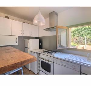 eine Küche mit weißen Geräten, einem Tisch und einem Fenster in der Unterkunft Aile de villa climatisée avec piscine in Porticcio
