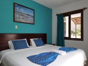a bedroom with a bed with blue walls and a window at Hotel LA GRAN TORTUGA - ᯤ STARLINK in Puerto Villamil +32 photos