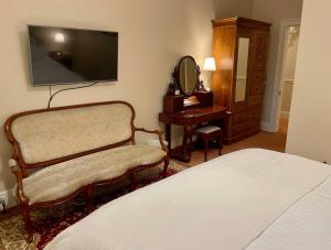 um quarto com uma cama, uma cadeira e um espelho em Rowan Brae Historic Guesthouse em Blackheath