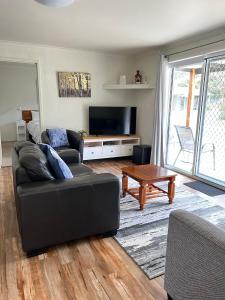 ein Wohnzimmer mit einem schwarzen Sofa und einem TV in der Unterkunft Willow Dene Holiday Apartments in Bright