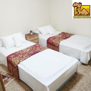 um quarto com três camas e um logótipo de cavalo na parede em Majido Hotel em Wadi Musa