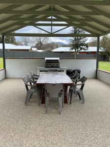 een houten tafel en stoelen onder een paviljoen bij Willow Dene Holiday Apartments in Bright