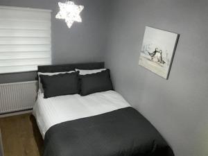 a bedroom with a black and white bed and a chandelier at Ideal Abode Greenfields in Chester