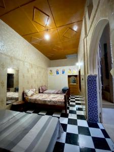 a bedroom with two beds and a black and white checkered floor at Riad Essalam in Rabat