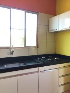 a kitchen with white cabinets and a sink and two windows at Lençóis Hospedagens in Barreirinhas