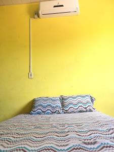 a bed with two pillows on it with a yellow wall at Lençóis Hospedagens in Barreirinhas