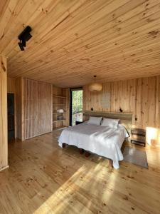 1 dormitorio con cama y techo de madera en Tripanko Lodge & Bungalows, en Pichilemu