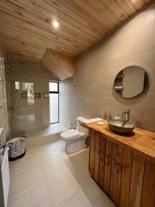 een badkamer met een wastafel, een toilet en een spiegel bij Tripanko Lodge & Bungalows in Pichilemu