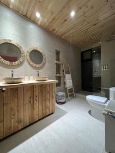 een badkamer met 2 wastafels en een toilet bij Tripanko Lodge & Bungalows in Pichilemu
