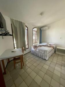 um quarto com uma cama, uma mesa e uma janela em Por do Sol Pousada Praia em São Luís