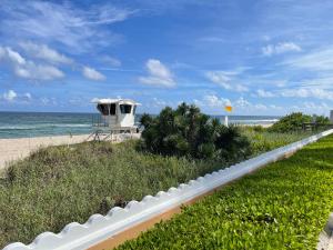a white fence next to a beach with a house at 4BR Downtown House Near Beach, Pet Friendly in West Palm Beach