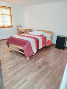 Schlafzimmer mit einem Bett und Holzboden in der Unterkunft ENEDE HOSTEL in Cusco