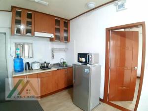 a kitchen with a stainless steel refrigerator and wooden cabinets at Mireya's 1BR condo at Zone Vill - Burnham Park in Baguio