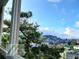 a view of a city from a window at Mireya's 1BR condo at Zone Vill - Burnham Park in Baguio