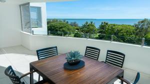 een houten tafel en stoelen op een balkon bij Waters Edge Apartment Cairns in Cairns