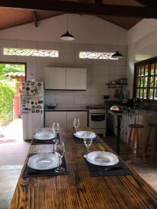 uma cozinha com uma mesa de madeira com pratos e copos de vinho em Casa Colmeia em Lençóis