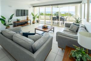 a living room with two couches and a table at Waters Edge Apartment Cairns in Cairns