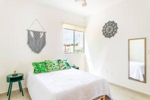een witte slaapkamer met een bed en een spiegel bij Lovely COZY Apt w/pool 2 Bedrooms. Great location! in Puerto Morelos
