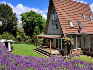 una casa con terraza y flores púrpuras en the Wooden A-frame in Hamilton, en Hamilton