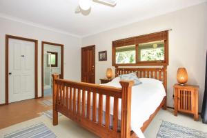 ein Schlafzimmer mit einem Holzbett und einem Fenster in der Unterkunft Semaphore Beach House in Hawks Nest