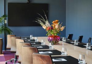 a conference room with a long table with a vase of flowers at Naumi Hotel Wellington in Wellington