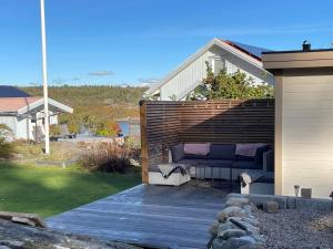 eine Terrasse mit einem Sofa auf einer Holzterrasse in der Unterkunft Holiday home HÅLTA in Kode
