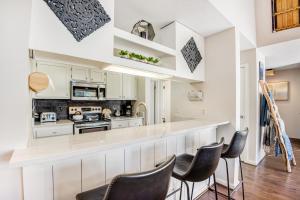 una cocina con armarios blancos y un bar con sillas negras. en Pines 2041 en Keystone