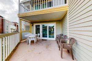 a patio with chairs and a table on a balcony at Victorian Condos Barefoot Beach Haven in Galveston