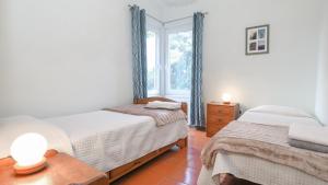 a bedroom with two beds and a window at Casa Cor de Rosa in Madalena