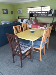 ein Esszimmer mit einem Tisch und Stühlen sowie ein Schlafzimmer in der Unterkunft Quail's Nest in Mangawhai