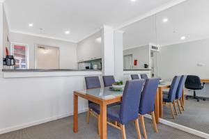 a dining room with a table and blue chairs at Comfy One Bedroom Apartment In Heart of The Rocks in Sydney +4 photos