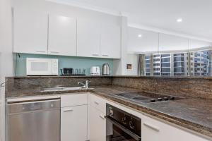 a kitchen with white cabinets and a counter top at Comfy One Bedroom Apartment In Heart of The Rocks in Sydney