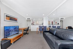 a living room with a couch and a tv at Comfy One Bedroom Apartment In Heart of The Rocks in Sydney