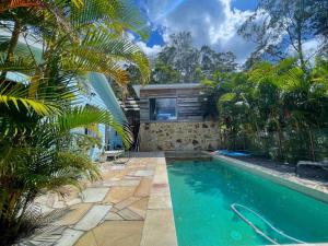 a swimming pool in a garden with a house at Golden Retreat Ultimate 5 Bed - Villa & Guesthouse in Uki