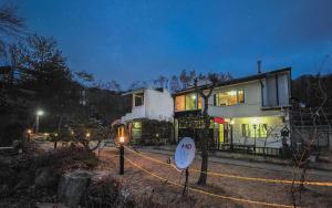 uma casa com uma corda amarela à volta à noite em Rest Pension em Pyeongchang