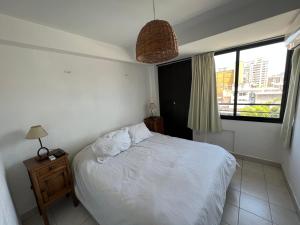 ein Schlafzimmer mit einem weißen Bett und einem Fenster in der Unterkunft APART BALCARCE in San Miguel de Tucumán