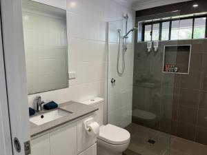 a bathroom with a shower and a toilet and a sink at Emina's Granny Flat in Woollamia