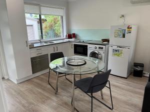 a kitchen with a glass table and a refrigerator at Emina's Granny Flat in Woollamia