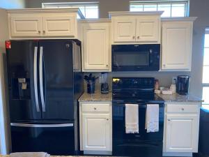 a kitchen with a black refrigerator and white cabinets at 10 min airport 15 min PD Canyon in Amarillo