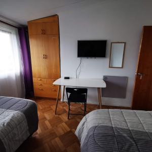 1 dormitorio con escritorio, TV y cama en Hostal Vivo Concepción, en Concepción
