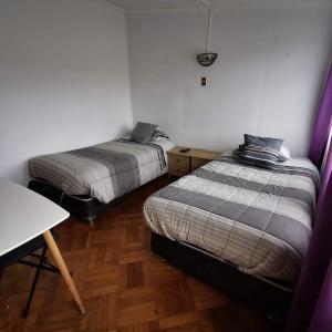 two beds in a small room with a table and a table at Hostal Vivo Concepción in Concepción