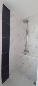 a shower in a bathroom with white marble tiles at Koh Lanta MaiKaew Villa in Ban Ru Yai