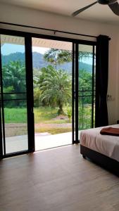 a bedroom with a bed and a large sliding glass door at Koh Lanta MaiKaew Villa in Ban Ru Yai