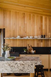 a kitchen with a counter and wooden walls at Upland Farm Luxury Cabins, Denmark Western Australia in Denmark
