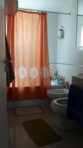 uma casa de banho com uma cortina de chuveiro laranja e um WC. em Rosario siempre estuvo cerca em Rosário
